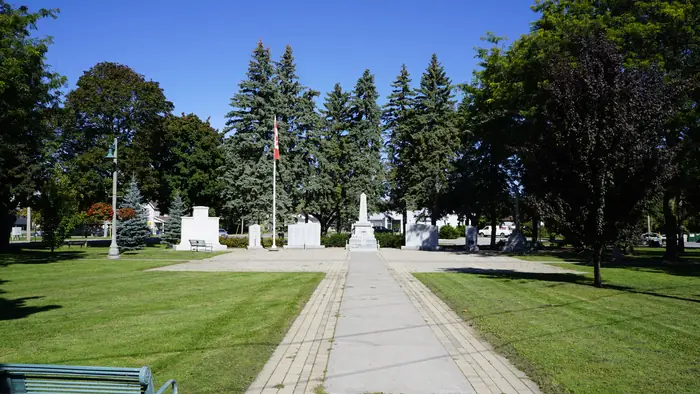 Green mowed lawns, spruce trees and a walkway at Memorial Park in Belleville