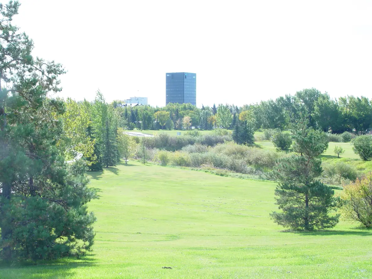 Wide mowed grass in Muskoseepi Park with downtown Grande Prairie behind
