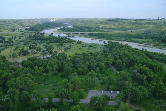 Trees, grass and the Oldman River in Indian Battle Park, seen from the High Level Bridge