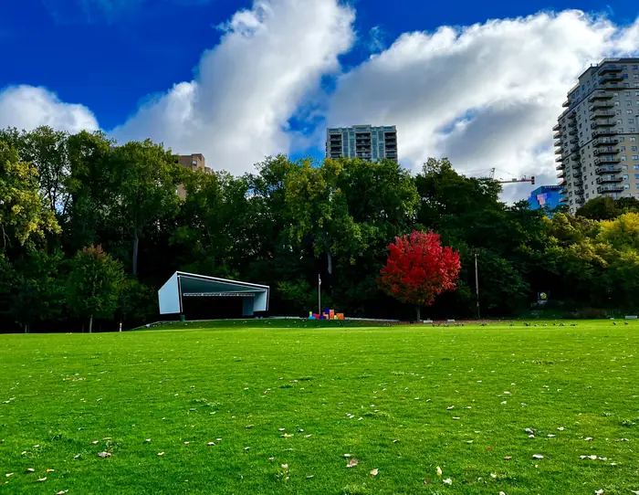 Wide, freshly mowed lawn at Harris Park near downtown London, Ontario, with trees and apartment towers behind it