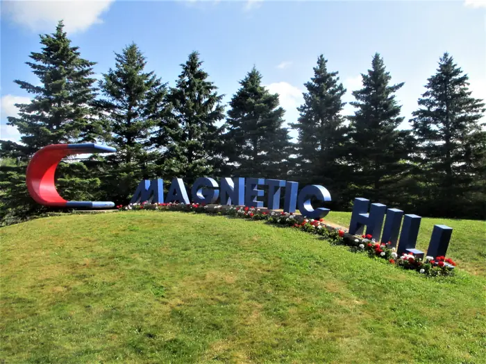 Magnetic Hill sign on a freshly mowed slope, the kind of lawn people hire the best landscaper in Moncton for