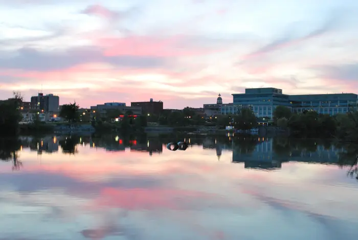 Downtown Peterborough reflected in the Otonabee River at dusk, a city the best landscaper in Peterborough knows street by street