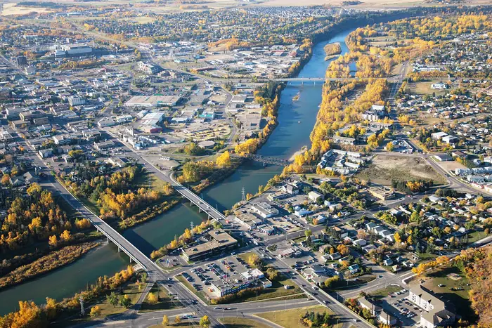 Aerial view of the Red Deer River in fall, with bridges and homes on both banks, the kind of yards that need the best landscaper in Red Deer