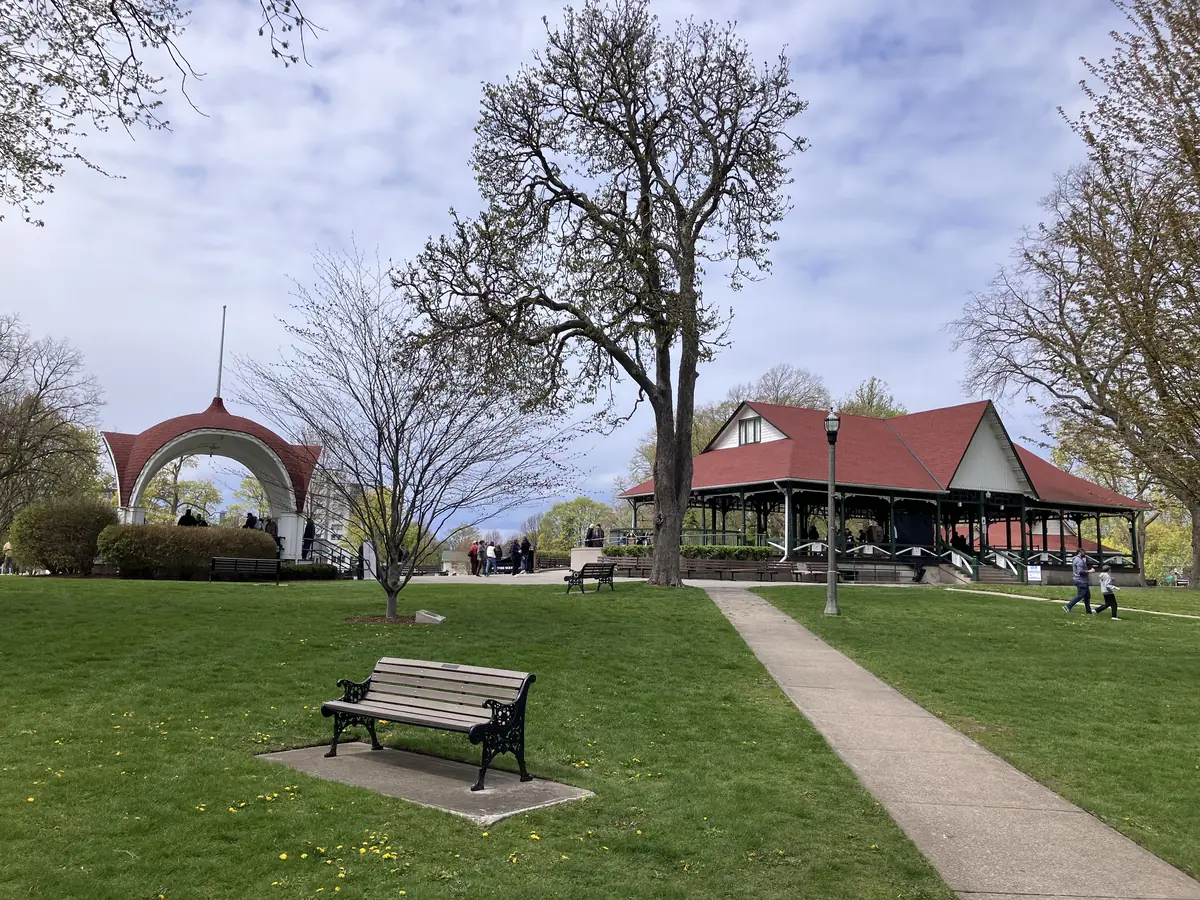 Wide mowed lawn, a bench and a pavilion in Montebello Park, St. Catharines