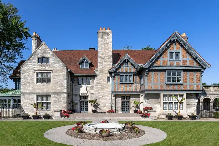 Green lawn and a round flower bed in front of Willistead Manor, the kind of yard people want the best landscaper in Windsor for